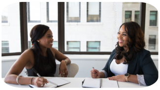 Two female African American colleagues work together at a table