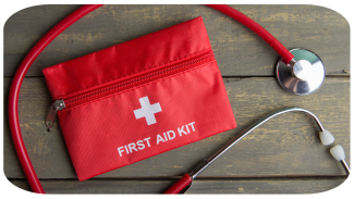 Red first aid kit and stethoscope on a wooden surface